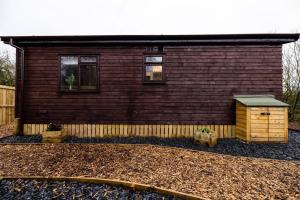 a small house with a building with two windows at The Woodland Lodge - Wood Fired Hot Tub and Firepit in Hambleton