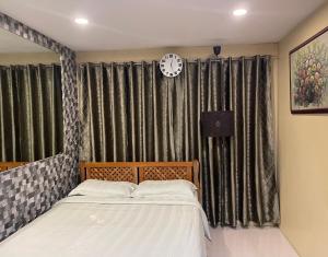 a bedroom with a bed and a clock on the wall at Cozy Studio Hotel-like Condominium at Megatower Residences in Baguio