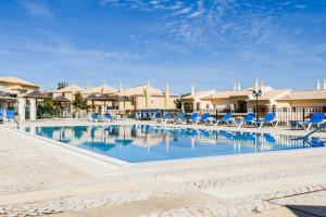 a pool at a resort with blue lounge chairs at Casa Lomy - Boavista Resort and Spa in Lagos