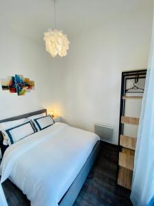 - une chambre avec un lit blanc et un lustre dans l'établissement Deux pièces proche Palais et plages, à Cannes