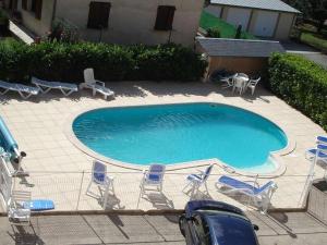 a swimming pool with chairs and lawn chairs at Hôtel Armony in Laissac