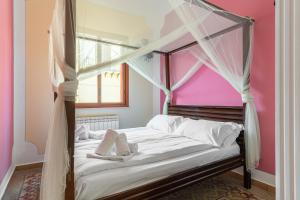 - une chambre avec un lit à baldaquin et un mur rose dans l'établissement Solemar Sicilia - Principe del Mare, à Santa Flavia