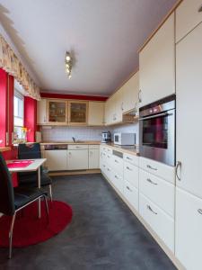 a large kitchen with white cabinets and a table at Benkelberg in Sitzerath