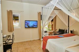 a hotel room with a bed, television, and bedside table at Kuredu Island Resort & Spa in Kuredu