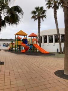 a playground with a slide in a park with palm trees at Casa Camar in Corralejo
