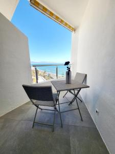 una mesa y una silla en una habitación con vistas al océano en Studio LE LUXE au soleil face à la mer, en Torremolinos