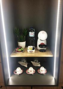 a shelf with cups and saucers and a coffee maker at Viseu Guest Inn in Viseu