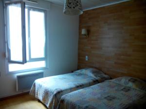 two beds in a room with a window at Hôtel Lamartine in Dijon