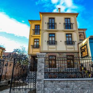 un edificio amarillo con ventanas negras y una valla en Vila Sonnet en Korçë