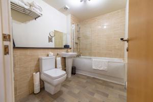 a bathroom with a toilet and a sink and a tub at Courtyard Mews in Wakefield