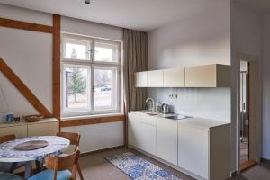 a kitchen with white cabinets and a table and a window at Vila Kollár Apartmán 15 in Dolný Smokovec