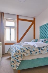 a bedroom with a bed with a blue headboard and a window at Vila Kollár Apartmán 15 in Dolný Smokovec