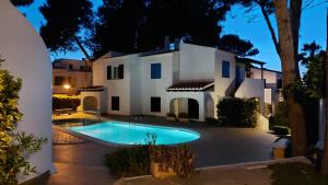 a villa with a swimming pool in front of a house at CALA BLANCA-TORRE BELLVER in Cala Blanca