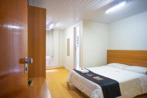 1 dormitorio con 1 cama y puerta de madera en Ano Bom Palace Hotel, en Barra Mansa