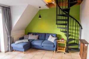 a living room with a blue couch and a green wall at Maisonette-Ferienwohnung Karla in Karlshagen