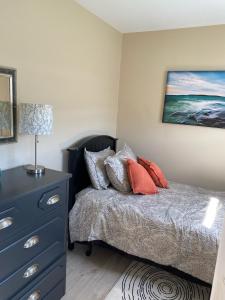 Un dormitorio con una cama con una cómoda azul y una pintura en Rocky Harbour Oceanfront, en Rocky Harbour