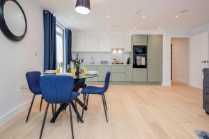 a kitchen and dining room with a table and blue chairs at Watford Cassio Deluxe - Modernview Serviced Accommodation in Watford