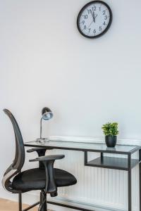 een glazen bureau met een stoel en een klok aan een muur bij Watford Cassio Deluxe - Modernview Serviced Accommodation in Watford