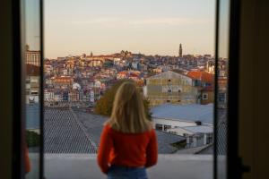 Una mujer mirando desde una ventana una ciudad. en Feel Porto Wine Essence Apartments, en Vila Nova de Gaia