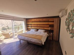 a bedroom with a large bed and a large window at Lodge Nueva Elqui in Pisco Elqui