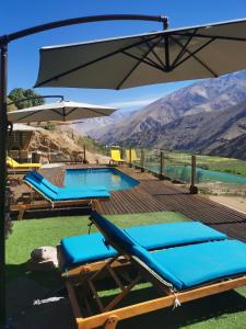 a pool with blue lounge chairs and an umbrella at Lodge Nueva Elqui in Pisco Elqui
