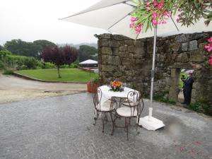 a table with two chairs and an umbrella at Paco de Pombeiro - Turismo de Habitacao in Felgueiras