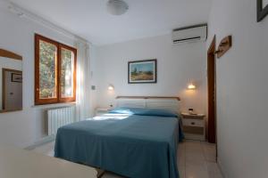 una camera con un letto blu e una finestra di Hotel Valle Verde a Procchio