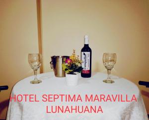 a bottle of wine and two glasses on a table at Hotel Septima Maravilla Lunahuana in Lunahuaná