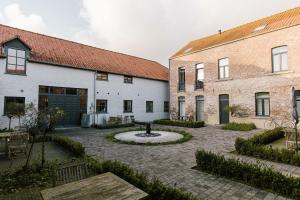 une cour avec une fontaine entre deux bâtiments dans l'établissement Hoeve de Reetjens - Le Marie, à Bilzen