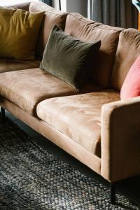 un sofá marrón con almohadas en la sala de estar en Hoeve de Reetjens - Le Marie, en Bilzen