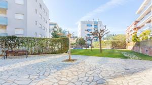 un parque con un banco y un árbol y edificios en 2Kis - Lloret de Mar, en Lloret de Mar