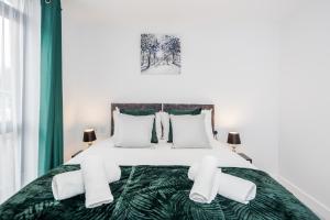 a white bedroom with a green bed with white pillows at Watford Cassio Luxury - Modernview Serviced Accommodation in Watford