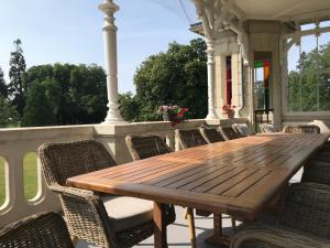 - une table et des chaises en bois sur une terrasse couverte dans l'établissement Chateau Vary, à Jarzé