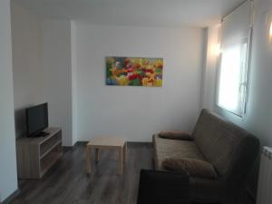 a living room with a couch and a tv at Apartamentos Turísticos Teruel in Teruel