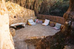 - un ensemble d'oreillers assis à côté d'un mur en pierre dans l'établissement EcoNature Dagaio Handmade Paradise, à Ericeira