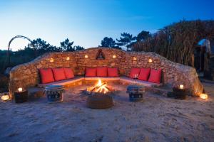 une tente en pierre avec un foyer extérieur et des oreillers rouges dans l'établissement EcoNature Dagaio Handmade Paradise, à Ericeira