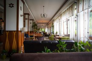 a waiting room with couches and tables and windows at Casa cu Tei - Sarata Monteoru in Sărata-Monteoru