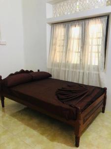 Cama de madera en habitación con ventana en Malabar home stay, en Jaffna