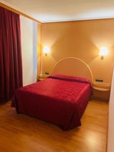 1 dormitorio con 1 cama con colcha roja en Hotel VillaPaloma, en La Virgen del Camino