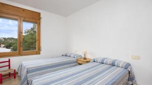 due letti in una stanza bianca con una finestra di I-23 - Calella de Palafrugell a Calella de Palafrugell