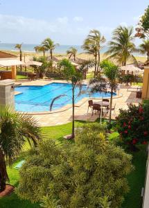 Blick auf einen Pool mit Palmen und das Meer in der Unterkunft Atlantic Palace Family inn in Aquiraz