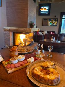 兹拉蒂博尔Vila Breg Zlatibor的一张桌子,上面放着两盘食物和一个壁炉 更多75张照片