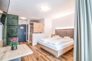 Un dormitorio con una cama y una mesa con un jarrón de flores en Hotel Sterzinger Moos en Vipiteno