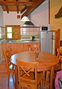 a kitchen with a wooden table with chairs and a refrigerator at Pedrazales Rural in Pedrazales