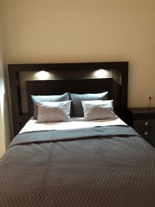 1 cama grande con cabecero negro y almohadas blancas en Hotel Finca San Nicolas, en San Salvador