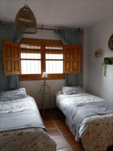 two beds in a room with two windows at Casa La Pizarra in Bubión