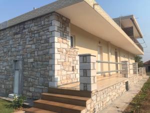 Casa con pared de piedra y porche de madera en Nereids Apartments-Pronoe, en Petalidi