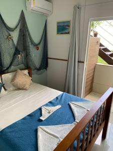 um quarto com uma cama com lençóis azuis e uma janela em Americano's Suítes em Arraial do Cabo