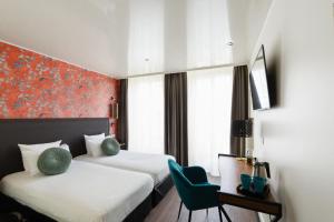 a hotel room with two beds and a chair at Moris Grands Boulevards in Paris