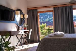 ein Schlafzimmer mit Bett, Schreibtisch und Fenster in der Unterkunft Angelika Elegant Hotel in Parga + 13 Fotos